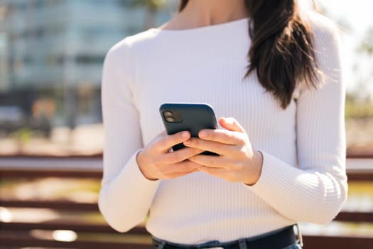 unrecognizable caucasian woman using mobile phone outdoors, concept of technology of communication and modern lifestyle