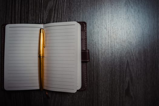 A notebook with a gold pen on the table in the candlelight. High quality photo