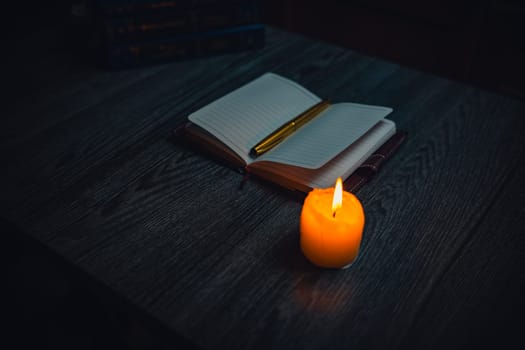 A notebook with a gold pen on the table in the candlelight. High quality photo