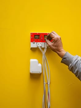 A technician closely examines and inspects various electrical equipment and components, surrounded by a vibrant yellow work environment