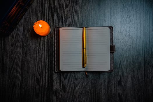 A notebook with a gold pen on the table in the candlelight. High quality photo