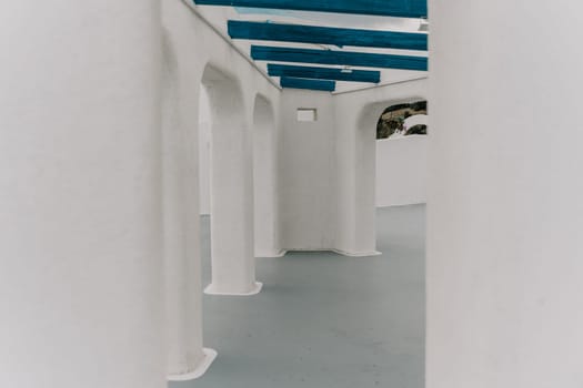 A blue and white building with a blue door sits on a balcony overlooking the ocean. The scene is serene and peaceful