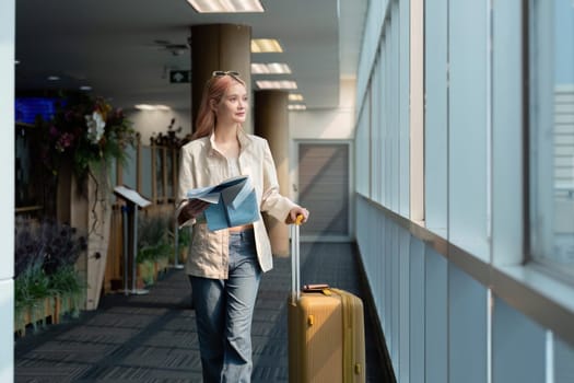 Asian woman with sunglasses holding map in airport terminal. Concept of travel, style, and anticipation.