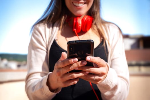 Satisfied with the results, the businesswoman walking on the street outside the office building, a young boss holds a phone in her hands, writes messages and reads news online, using an app.