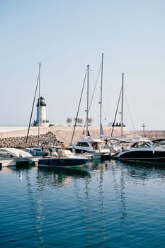 Row of motor boats moored at a breakwater with a lighthouse. High quality photo