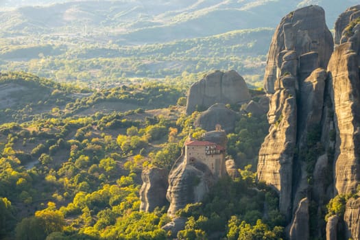 Greece. Sunny summer evening in the Kalambaka valley. Stone gazebo and small monastery with red roofs on the rock