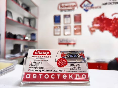Kirov, Russia - May 13, 2024: A car service companys business card sits on a counter in an office decorated with maps and automotive products