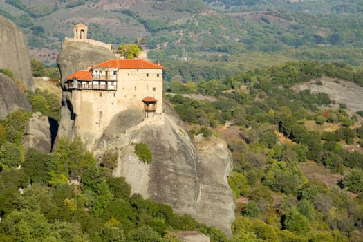 Greece. Sunny summer day in the Kalambaka valley. Stone gazebo and small monastery with red roofs on the rock