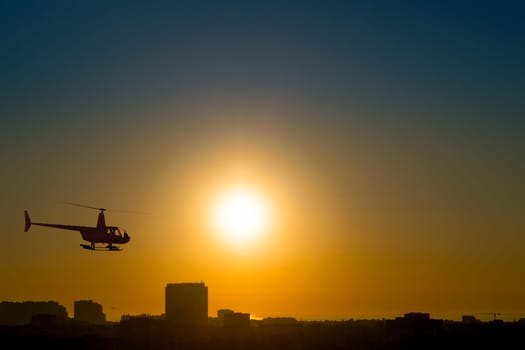 Ukraine. Sunrise in a clear sky over the coastal city of Odessa. Helicopter silhouette