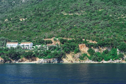 Sea view of low rise houses on the hill or close to the beach surrounded by a green forest in Lefkada Ionian Island Greece.