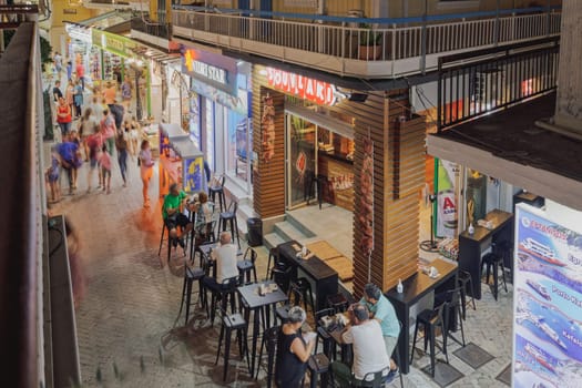 Lefkada, Greece - July 5 2021: Elevated night view of a pedestrian area with crowd and shops including Souvlaki comfort food in Ionian Island.