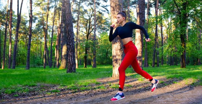 A young woman is running through the park in a sports suit.