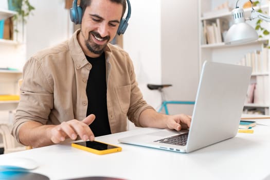 Smiling business man working on laptop at home office. Young student or remote teacher using computer remote studying, virtual training, watching online education webinar at home office. High quality photo