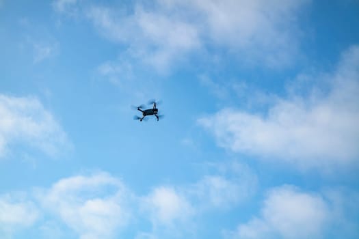 Small drone flying in the blue sky.