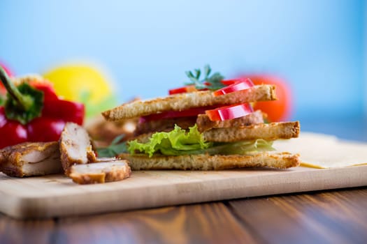 fried toast with chicken, salad, greens on a wooden table .