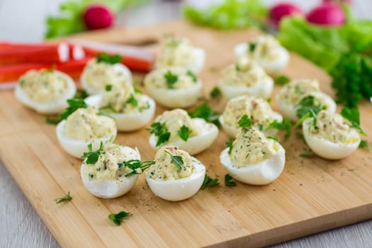 stuffed eggs, deviled eggs on a wooden table .