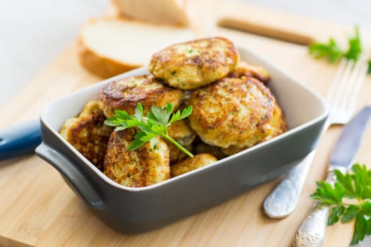 fried meat cutlets in a ceramic form on a wooden table .