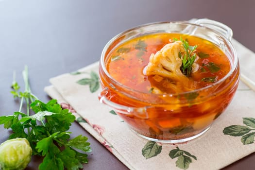 vegetable soup with Brussels sprouts and cauliflower, in a glass plate on a wooden table .