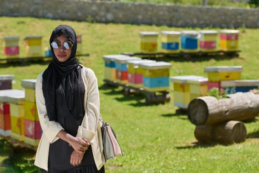 African American Muslim woman in hijab explores natural bee farms for honey production, blending tradition with sustainability in the serene countryside.