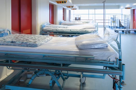 Clean hospital beds covered with film, ready for new patients. Hospital and nursing concept.