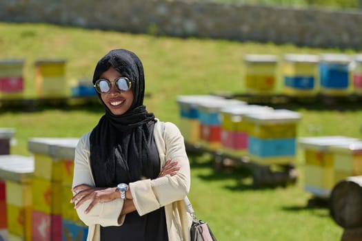 African American Muslim woman in hijab explores natural bee farms for honey production, blending tradition with sustainability in the serene countryside.