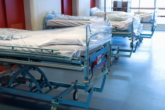 Clean hospital beds covered with film, ready for new patients. Hospital and nursing concept.