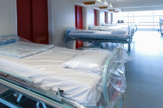 Clean hospital beds covered with film, ready for new patients. Hospital and nursing concept.