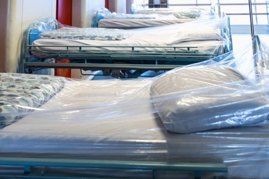 Clean hospital beds covered with film, ready for new patients. Hospital and nursing concept.