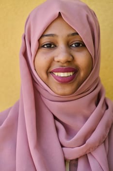 A Middle Eastern girl wearing a hijab, with a bright smile and a pink headscarf, captured in a close-up portrait exuding joy and positivity.