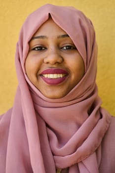 A Middle Eastern girl wearing a hijab, with a bright smile and a pink headscarf, captured in a close-up portrait exuding joy and positivity.