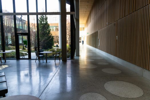 Hall and corridor in a modern building with large glass windows and a sitting area.