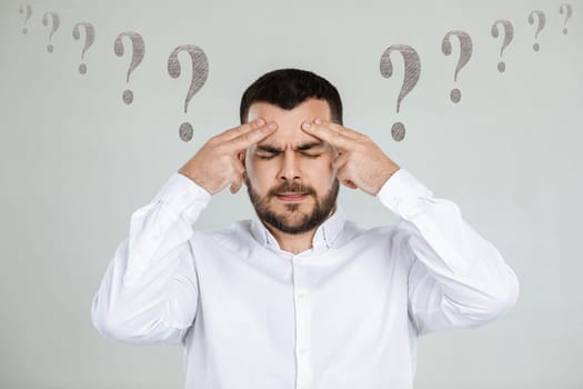 portrait of doubtful bearded man in white shirt asking questions on gray background.