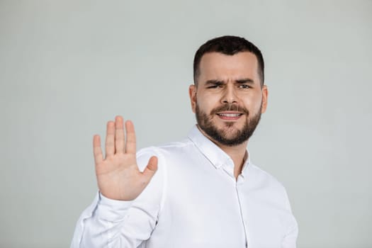 handsome bearded man showing stop gesture on gray background.