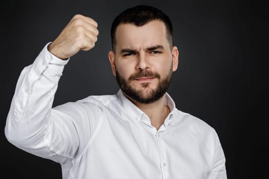 portrait of angry bearded man on black background. he threatens someone