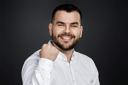 young happy handsome bearded man raising fist on black background. excited expressing winning gesture