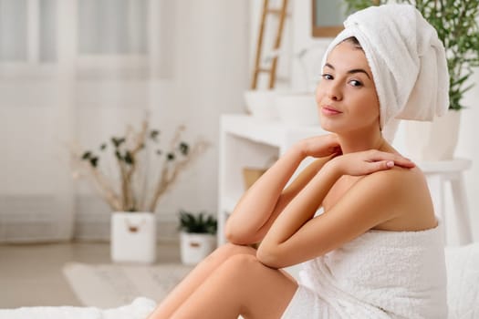 beautiful young woman with bath towel sitting on bed. copy space