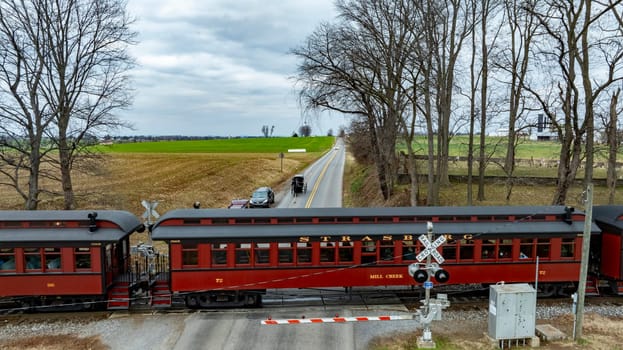 Ronks, Pennsylvania, USA, December 30, 2023 - A Historic Train Crossing Rural Road with an Amish Horse-Drawn Carriage