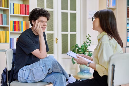 Female psychologist working with young male college student in office educational building. Mental health of youth, social service, psychology, psychotherapy, behavior, support treatment counselling