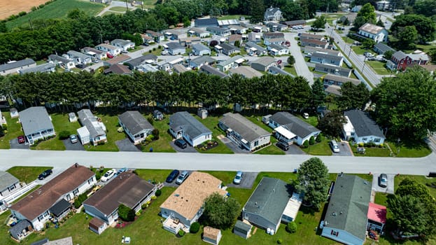 Overhead aerial view of a suburban Mobile, Prefab, Manufactured, neighborhood park, featuring rows of homes, neatly trimmed lawns, and parked cars