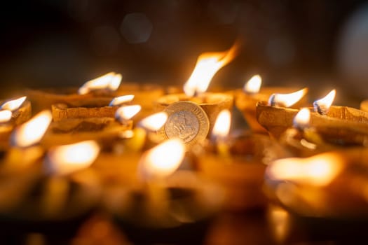 macro shot showing a circle of diya oil lamps around a rupee coin showing the offerings and prayers to the hindu wealth goddess lakshmi in India