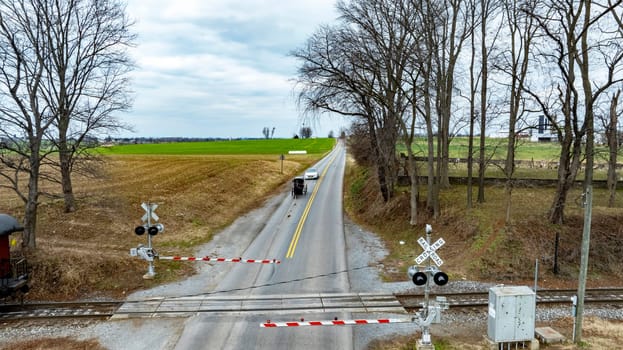 A Rural Road with An Amish Horse-Drawn Carriage at Railroad Crossing