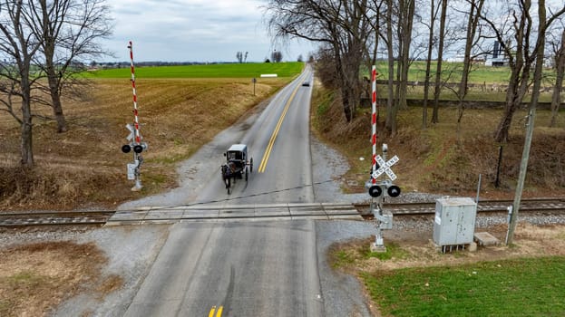 A Rural Road with An Amish Horse-Drawn Carriage at Railroad Crossing