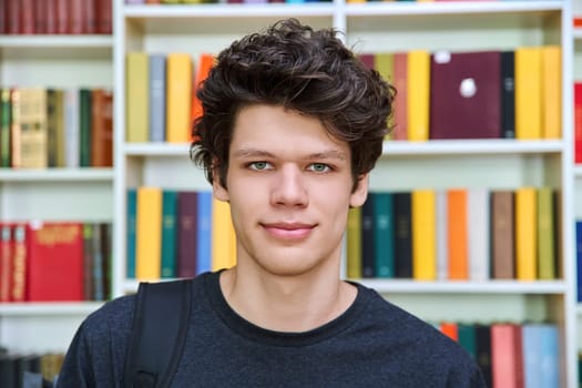 Headshot portrait of confident handsome college student guy inside library of educational building. Education, youth, lifestyle concept