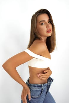 Young model woman in white underwear and jeans posing on white studio background