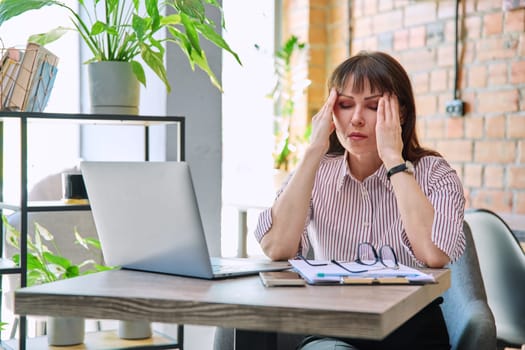 Mature tired worried tense woman at workplace experiencing stress headache. Health problems older age hormonal diseases mental difficulties migraine stressful job, depression anxiety pain injury shock