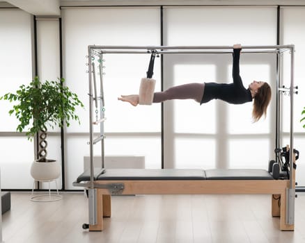 Caucasian woman doing aerial exercises on a reformer machine