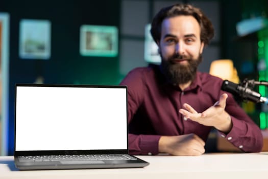 Close up shot of mockup laptop being assessed by cheerful tech expert talking about parts used inside. Focus on isolated screen notebook reviewed by man in blurry background for technology channel