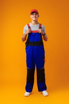 Full length shot of a young male worker in uniform on yellow background in studio