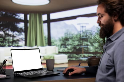 Young billionaire looks at white display layout on laptop, getting cozy in his extravagant alpine villa. Influential entrepreneur uses computer to check blank copyspace screen on pc, teleworking.