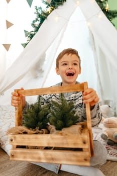A little boy lying in a children's wigwam decorated for Christmas with gifts